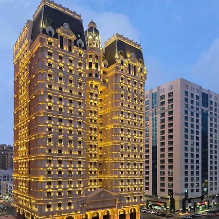 皇家玫瑰酒店 阿布扎比 外观 照片 The image shows a beautifully illuminated building that has an ornate architectural style, featuring golden lights that highlight its elaborate facade. The building appears to be quite tall and is likely a hotel or a high-end residence. In the backgr