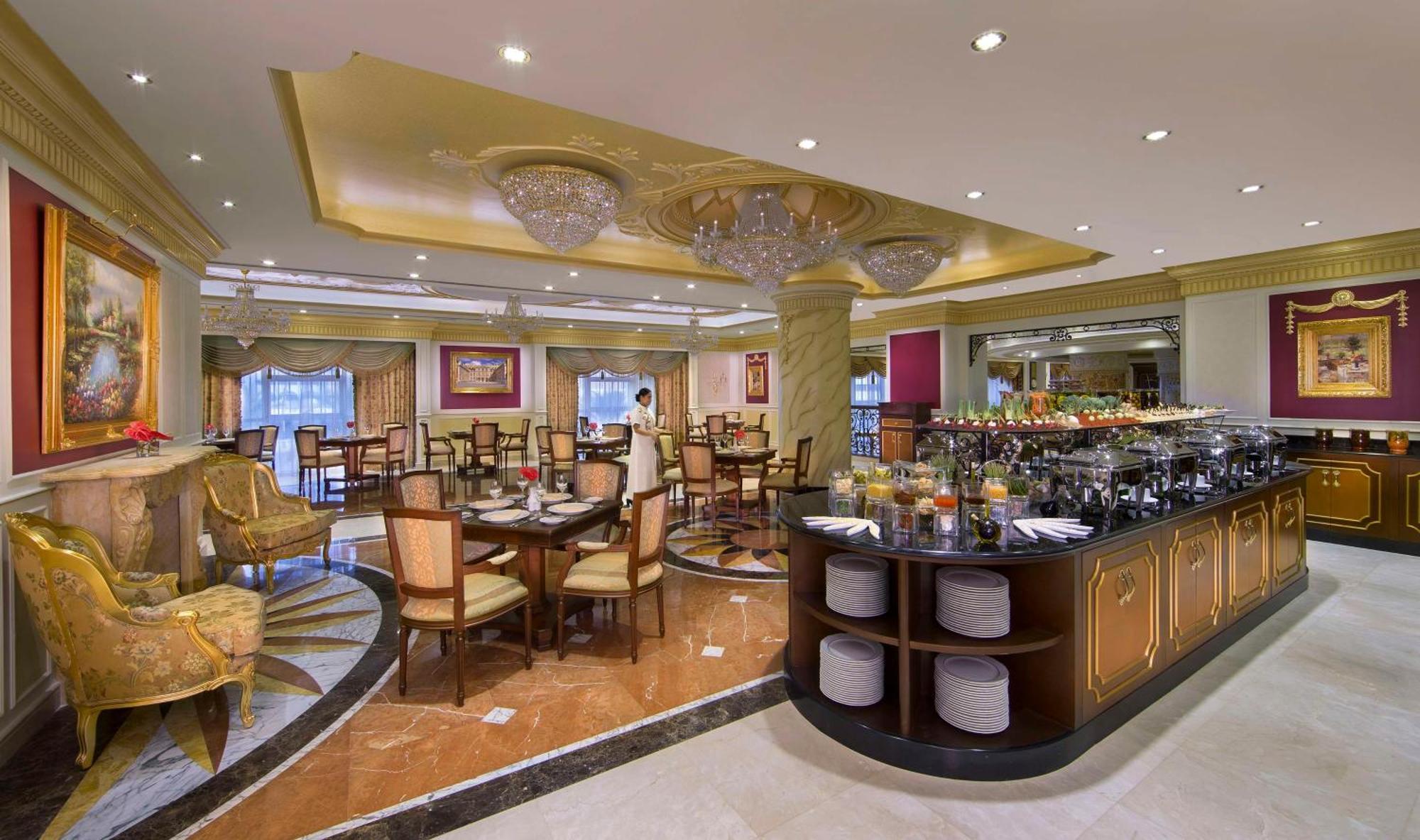 皇家玫瑰酒店 阿布扎比 外观 照片 The image shows the interior of an elegant restaurant. It features a spacious dining area with several tables and chairs arranged neatly. The decor includes ornate chandeliers hanging from the ceiling and stylish lighting that adds a warm ambiance to