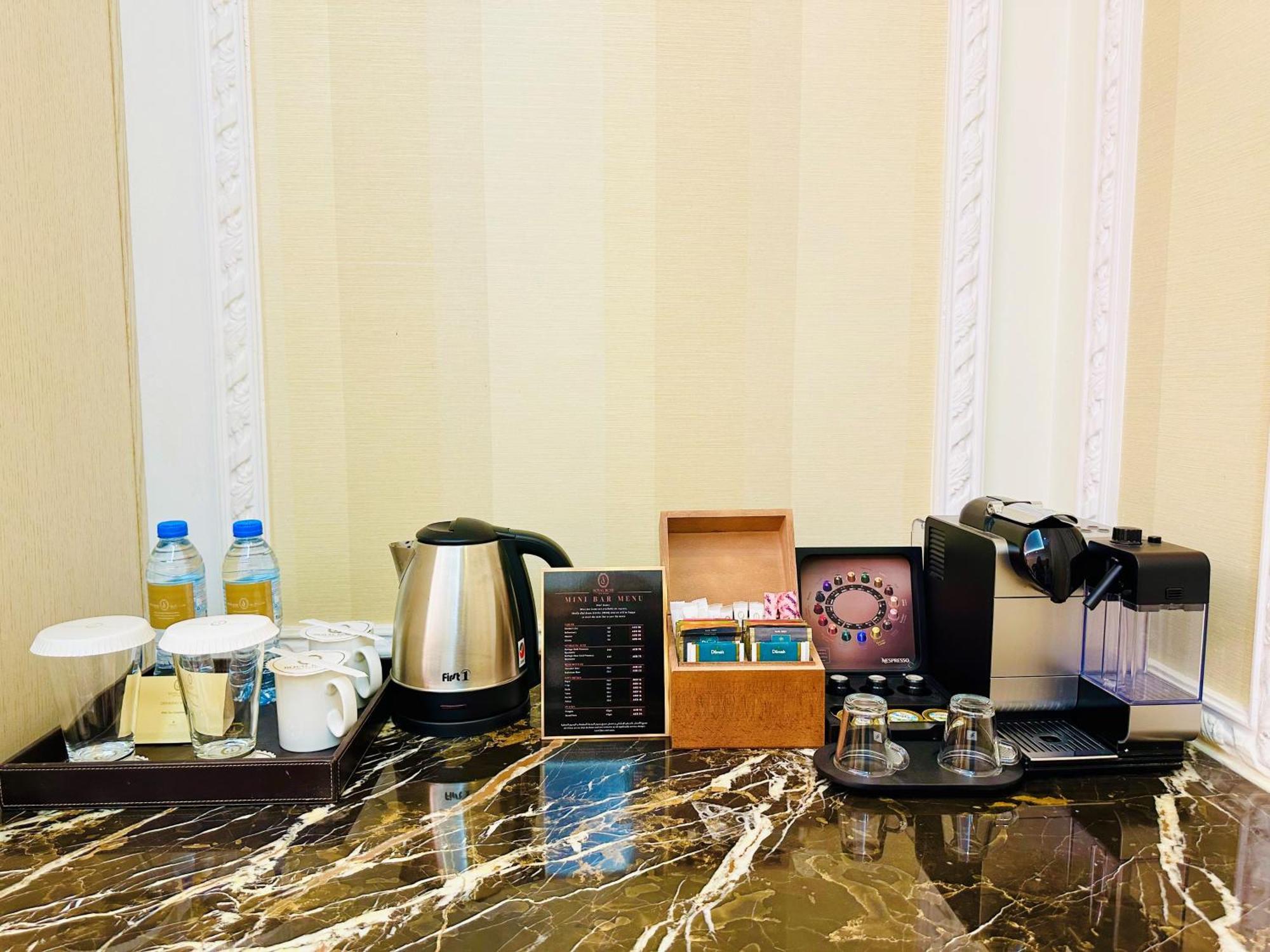 皇家玫瑰酒店 阿布扎比 外观 照片 The photo shows a hotel or room beverage station on a marble countertop. It includes:

- Two bottles of water.
- A kettle for boiling water.
- Two cups and a small container, likely for sugar or cream.
- A menu or information card detailing drink opt